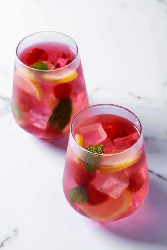Two glasses of pink lemonade with fruit and ice on a marble surface; Attribution - <a href="https://www.freepik.com/free-photo/raspberry-lemonade-drink_30501425.htm#fromView=search&page=3&position=7&uuid=b19ca59d-13a9-42be-925a-152dc2c44a59&query=rose+sangria">Image by chandlervid85 on Freepik</a>