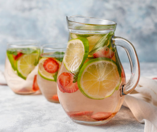 Clear glass pitcher filled with a refreshing drink containing lime slices and strawberries on a light background; Attribution - <a href="https://www.freepik.com/free-photo/fresh-lime-strawberry-mint-infused-water-cocktail-detox-drink-lemonade-summer-drinks-health-care-concept_6144199.htm#fromView=search&page=2&position=3&uuid=47004031-0c90-4321-967a-3c9d9ac3e4ea&query=white+sangria">Image by azerbaijan_stockers on Freepik</a>